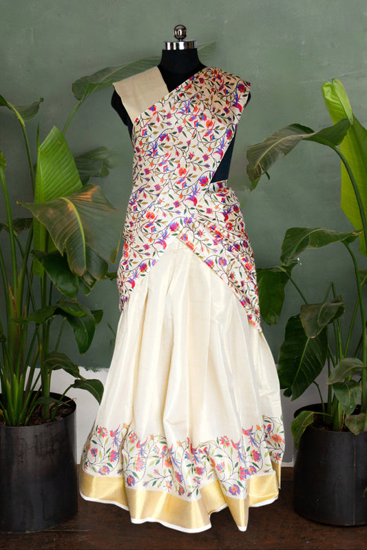 Sari with floral pattern on a mannequin against a green wall with plants.